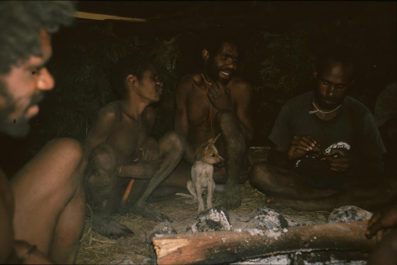 BD/166/109 - 
Dog with men in circle around wood fire

