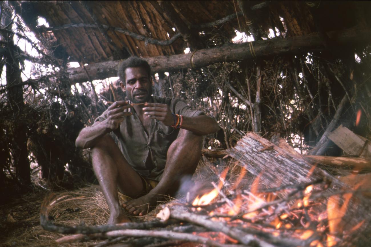 BD/166/409 -
Papua man in shirt next to a fireplace