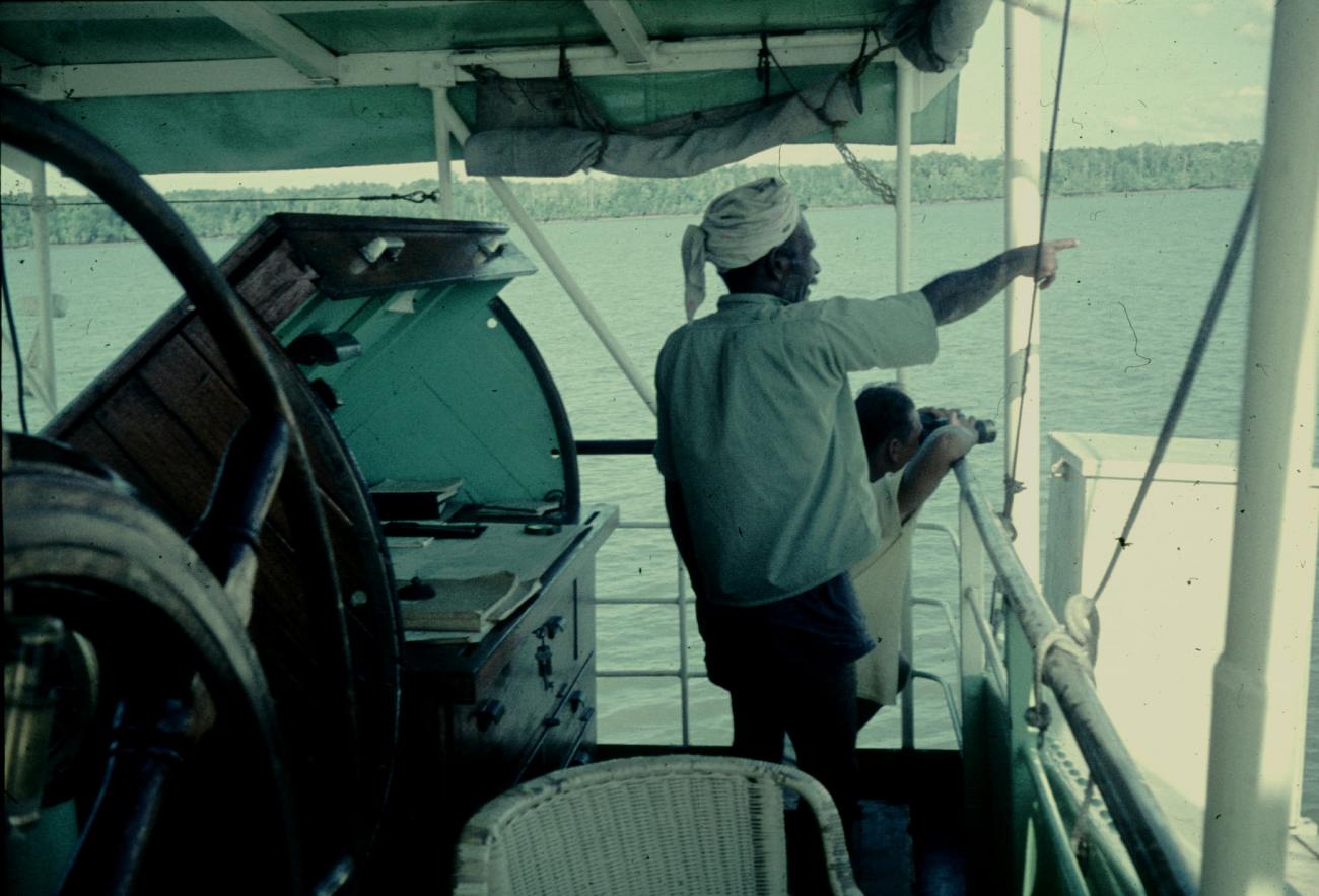 BD/144/435 - 
Foto genomen op schip, man wijst iets aan
