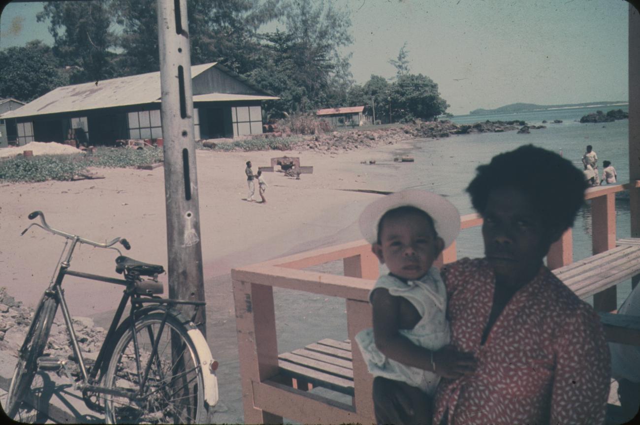 BD/144/619 - 
Moeder met kind, kust op achtergrond
