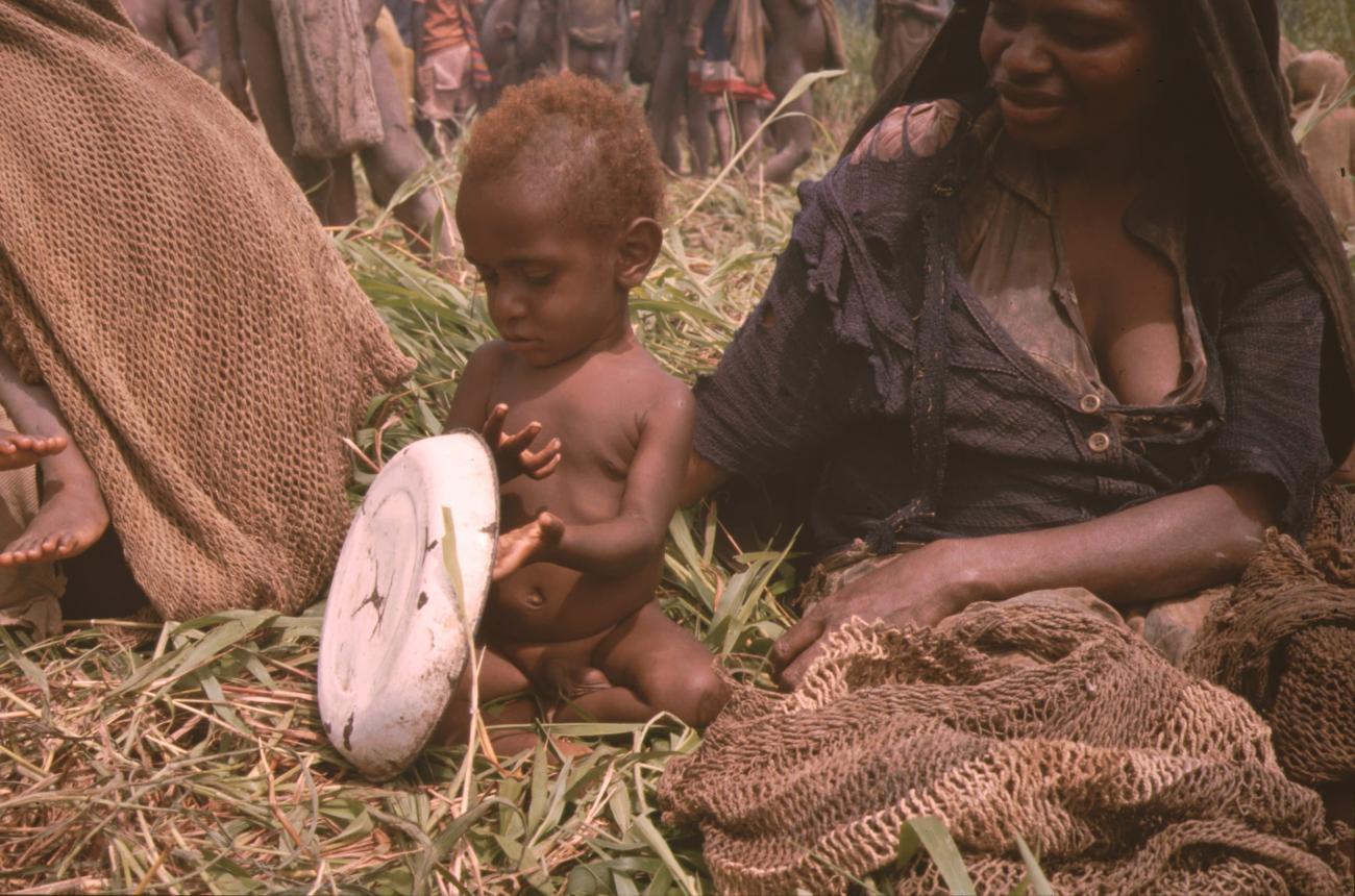 BD/132/134 - 
kind speelt met een bord naat moeder
