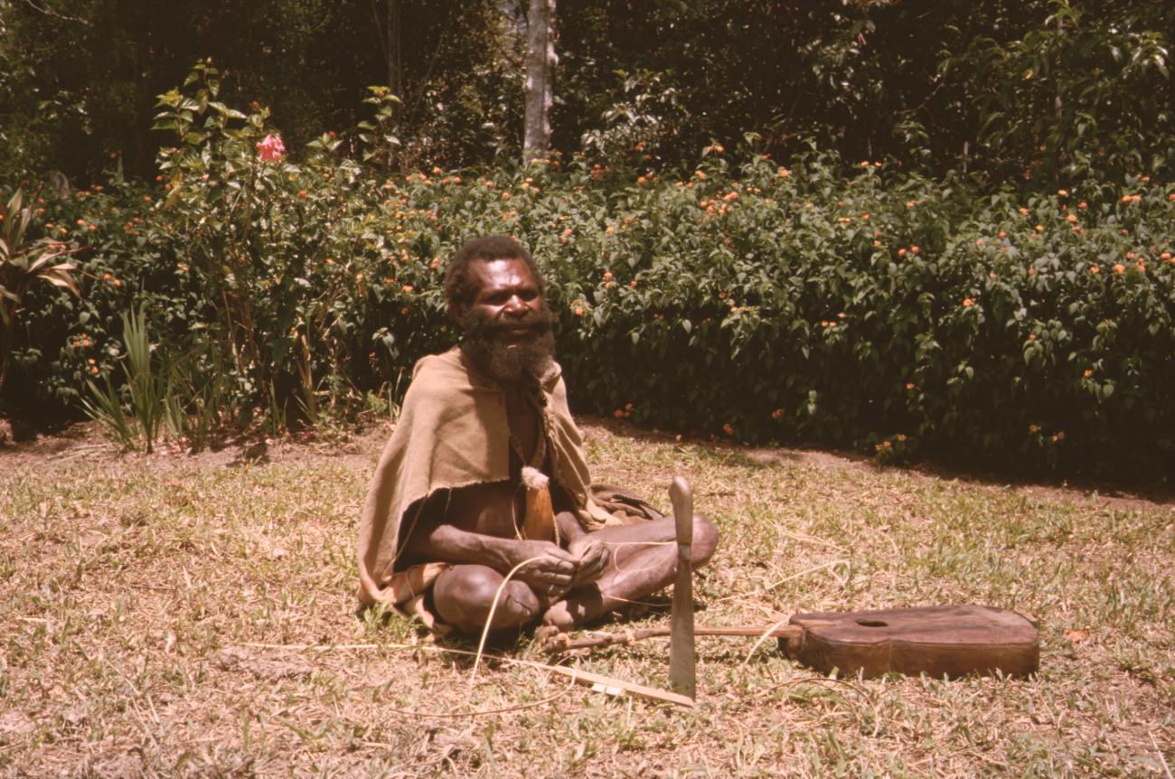 BD/132/173 -
zittende Papua met peniskoker, machete en gitaar