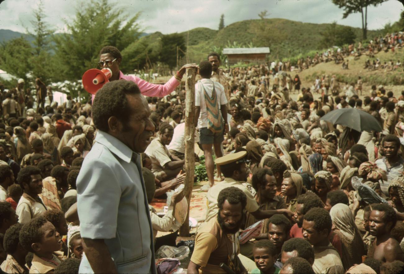 BD/132/50 -
groepsfoto van papua's en man met megafoon