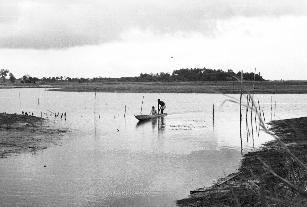 BD/133/871 - 
Prauw varend op de rivier met Papoea en westerse passagier
