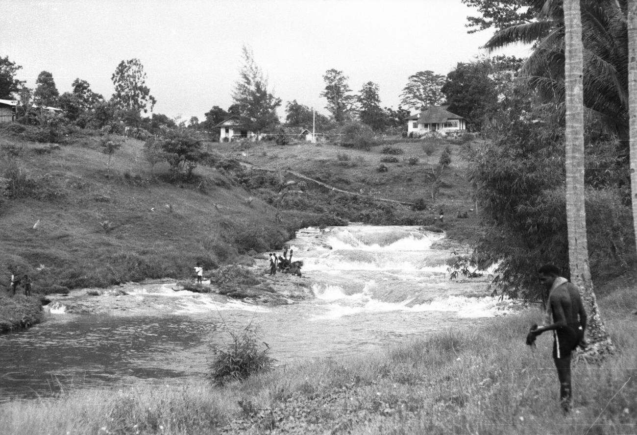 BD/133/907 - 
Rivier met stroomversnellingen bij een nederzetting

