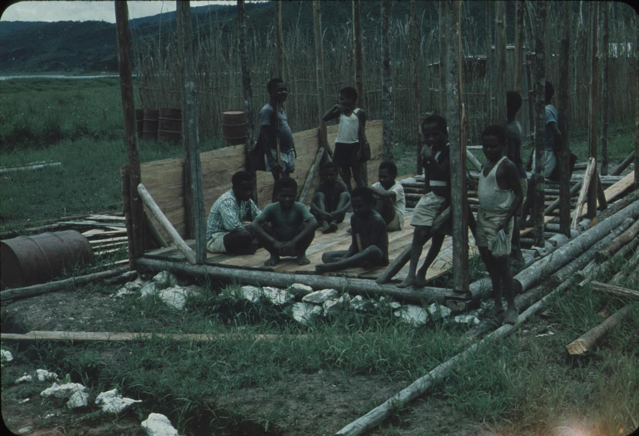 BD/248/165 - 
groep zittende mannen in het skelet van te bouwen huis
