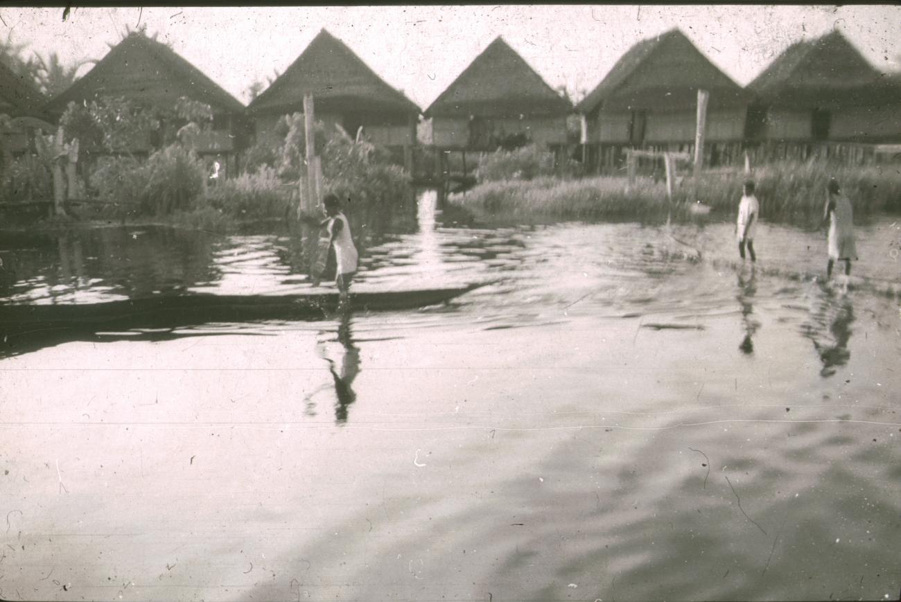 BD/309/351 -
Paalwoningen aan de rivier met twee prauwen in het dorp Kasueri