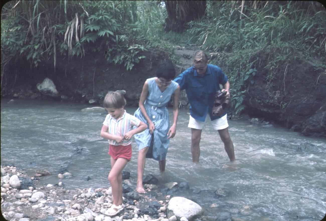 BD/171/280 - 
Westerse man, vrouw en kind waden door rivier.

