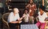 BD/309/97 Dorp Teminabuan, westerse man met echtpaar en kind op veranda