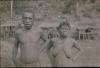 BD/309/194 Man en vrouw met op de achtergrond traditionele paalwoningen