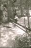 BD/309/314 Man zittend op een boomstam die over het water ligt 